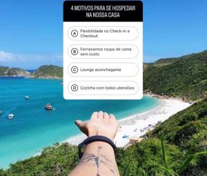 a picture of a beach with a person pointing at the ocean at Nossa Casa Arraial HOSTEL e SUÍTE in Arraial do Cabo