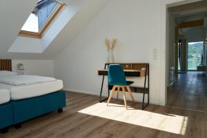 a bedroom with a bed desk and a blue chair at Appartements am See in Maria Wörth