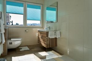a bathroom with a sink and a toilet and a window at Appartements am See in Maria Wörth