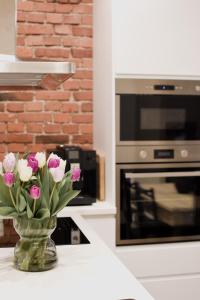 a vase filled with pink and white flowers on a counter at Vaksali Apartment! in Viljandi