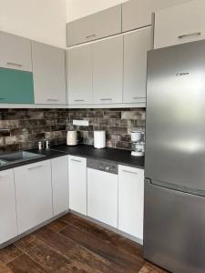 a kitchen with white cabinets and a stainless steel refrigerator at Koroni Luxury Apartment in Koroni