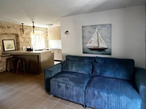a blue couch in a living room with a boat painting on the wall at Sailor's apartment in Supetar