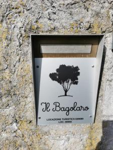 a sign on a stone wall with a tree at Il Bagolaro in Feriole
