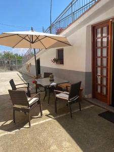 een patio met een tafel en stoelen en een parasol bij The Gods Brothers in Agerola