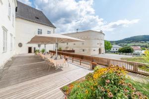 eine Holzterrasse mit Stühlen und Sonnenschirmen vor einem Gebäude in der Unterkunft Residenz Schloss Pöggstall in Pöggstall