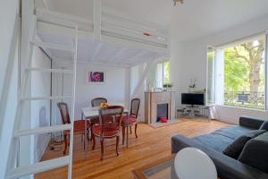 een woonkamer met een bank en een tafel met stoelen bij Charming Bright Studio in luxurious 16th in Parijs
