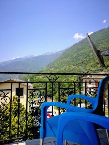 a blue chair on a balcony with mountains in the background at Belandin Ristorante Hotel in Teglio