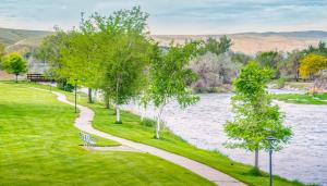 ザーモポリスにあるMay 29 and May 30 Great Rates, Amenity Heaven, You'll Love It, An Exceptional Wyoming Stay, Thermopolis River Walk Home at Hot Springs State Park, Where The Fisherman Stayの木々やベンチのある川の横の小道