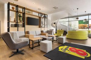 a lobby with chairs and tables and a tv at Super 8 by Wyndham Koblenz in Koblenz
