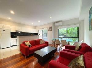 a living room with red couches and a table at Love Love Love ^^ in Hornsby