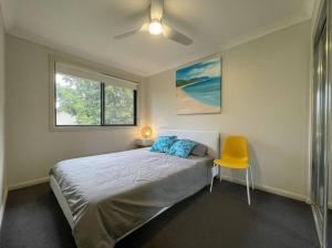 um quarto com uma cama e uma cadeira amarela em Love Love Love ^^ em Hornsby