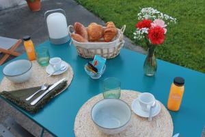 einen blauen Tisch mit einem Korb Brot und einem Blumenkorb in der Unterkunft La Naillousaine in Nailloux