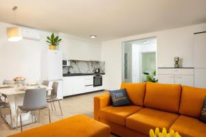 a living room with an orange couch and a kitchen at Apartman Oliva and Studio Delux for a family with swiming pool, free parking, terace with view at the sea in Podstrana