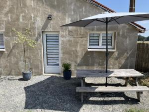 a picnic table with an umbrella in front of a building at Logement entier à la campagne proche du circuit et du zoo de la Flèche in Yvré-le-Pôlin
