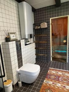 a bathroom with a toilet and a tiled wall at Mėta House in Merkinė
