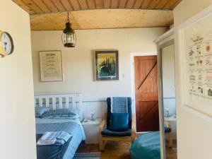 1 dormitorio con 1 cama y 1 silla azul en The Old Boathouse at Bunbeg Harbour, en Bunbeg