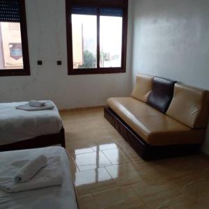 um quarto com um sofá, uma cama e janelas em Appartement propre et spacieux Tan Tan Plage El Ouatia em Tan-Tan Plage