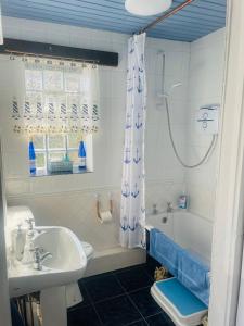 W łazience znajduje się umywalka, wanna i prysznic. w obiekcie The Old Boathouse at Bunbeg Harbour w mieście Bunbeg