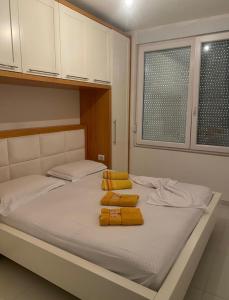 a bed with yellow pillows on it in a room at Beach Luxury Apartment Shëngjin in Lezhë