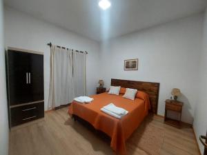 Schlafzimmer mit einem Bett mit orangefarbener Bettwäsche und einem TV in der Unterkunft Departamento Cafayate in Cafayate