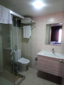 a bathroom with a shower and a toilet and a sink at Grand Faik Hotel in Cesme