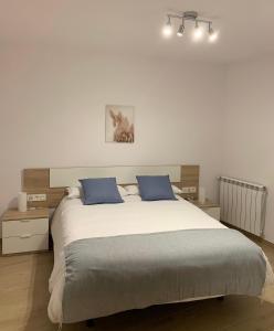 1 dormitorio con 1 cama grande y 2 almohadas azules en CAL JAN - La Muralla en Bellver de Cerdanya 