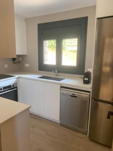 a kitchen with white cabinets and a sink and a window at CAL JAN - La Muralla in Bellver de Cerdanya