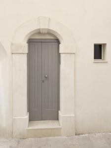 a gray door in an archway on a white building at WePuglia - Al Castello di AMEC - Apt Marika in Monopoli