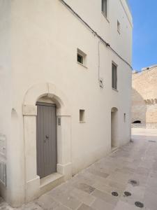 a white building with a gray door on the side at WePuglia - Al Castello di AMEC - Apt Marika in Monopoli