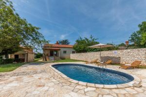 a pool with an umbrella and chairs and a house at Casa Laurales in Veli Turini