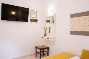 een witte kamer met een televisie en een kruk bij Evaggelia rental apartments in Skotina