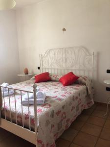 Schlafzimmer mit einem weißen Bett und roten Kissen in der Unterkunft Il giardino delle rose in Spello