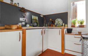 eine Küche mit weißen Schränken und einer schwarzen Wand in der Unterkunft Gorgeous Home In Aramon With Kitchen in Aramon