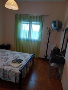 a bedroom with a bed with a green curtain and a television at THEO house in Kyllini Zakynthos in Kyllini