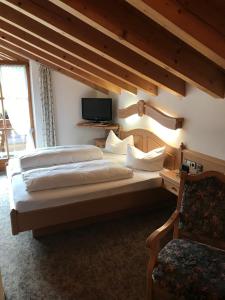 a bedroom with two beds and a tv and a chair at Gästehaus Schwarzlofer in Reit im Winkl +105 photos