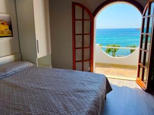 a bedroom with a bed and a view of the ocean at Casale fronte mare - villa with swimming pool in front of the beach in Porto Columbu - Perdʼe Sali +60 photos