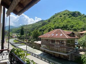 une maison sur une rivière avec une montagne en arrière-plan dans l'établissement Ralin Apart, à Prizren