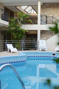 una gran piscina con sillas y un edificio en Hotel Suite & Spa Verdesolaro en Villa Elisa