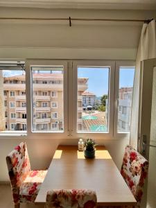 una sala da pranzo con un tavolo e due sedie e due finestre di Mint Apartment a Tivat