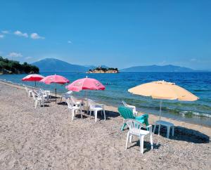 a group of chairs and umbrellas on a beach at Nord Guesthouse in Neos Pirgos