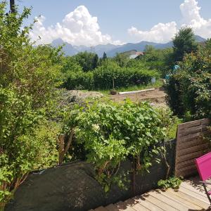 a garden with a bench and trees and mountains at Appartement entre lac et montagnes in Saint-Paul-en-Chablais