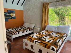 two beds in a room with a window at Cabaña milenio 1 in Moniquirá
