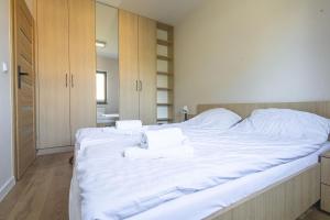 a large bed with white sheets and towels on it at Brzeska 22 in Łódź