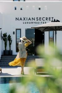 una mujer con un vestido amarillo de pie junto a una piscina en Naxian Secret, en Naxos Chora