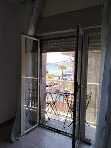 een glazen schuifdeur naar een balkon met een tafel bij FAMILY HOUSE Letojanni Taormina in Letojanni