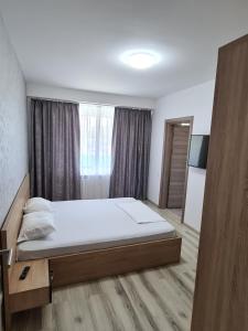 a bedroom with a bed and a large window at C&Y Marco Apartments in Mamaia