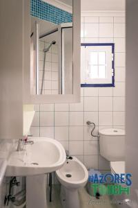 a white bathroom with a sink and a toilet at Casa da Rocha in Angra do Heroísmo