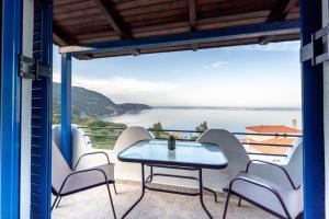 einen Balkon mit einem Tisch und Stühlen sowie Meerblick in der Unterkunft Amazing View in Akhladherí