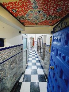 a hallway with a tile floor and a blue door at DAR AMAN CHEFCHAOUEN in Chefchaouene