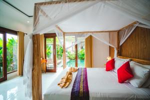een slaapkamer met een hemelbed met rode kussens bij Pondok Ubud Nia Cahya in Tegalalang
